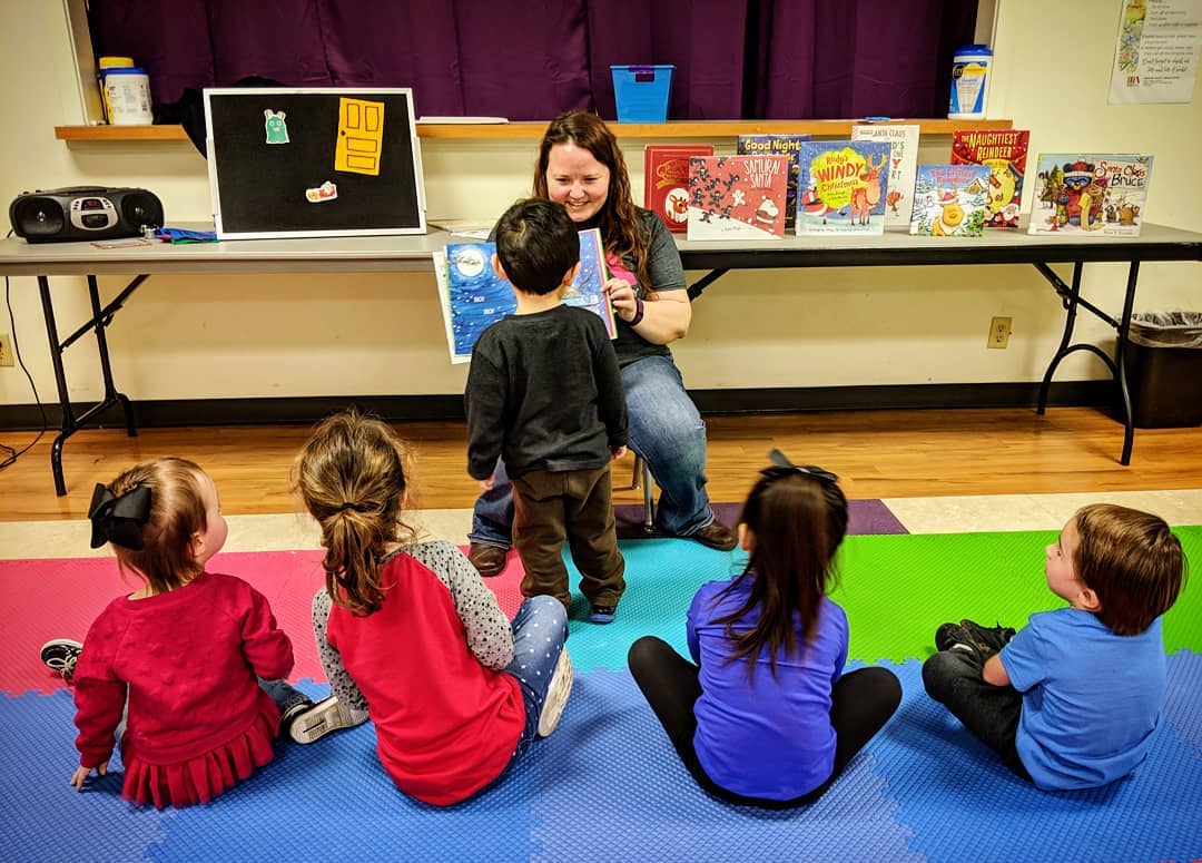 Woman reading a picture book to a group of children
