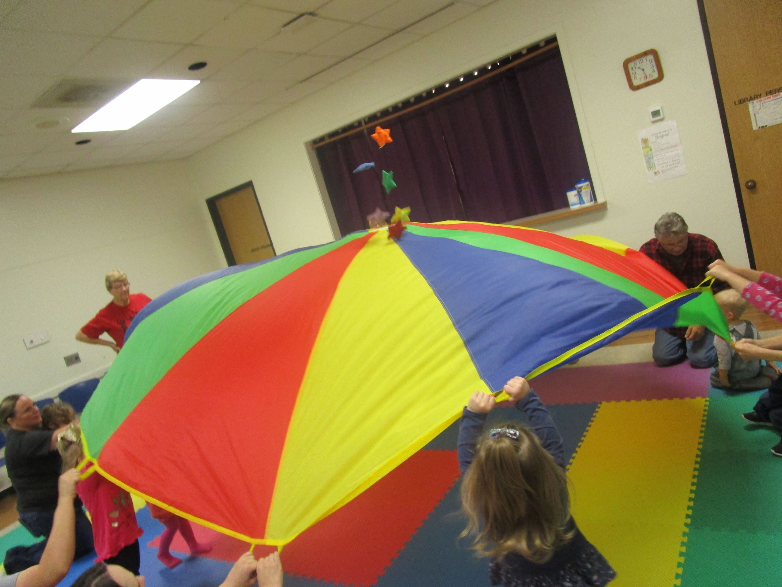 Kids and adults bouncing stars on a parachute